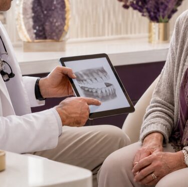 Dentist discussing dentures and dental implants with an older patient